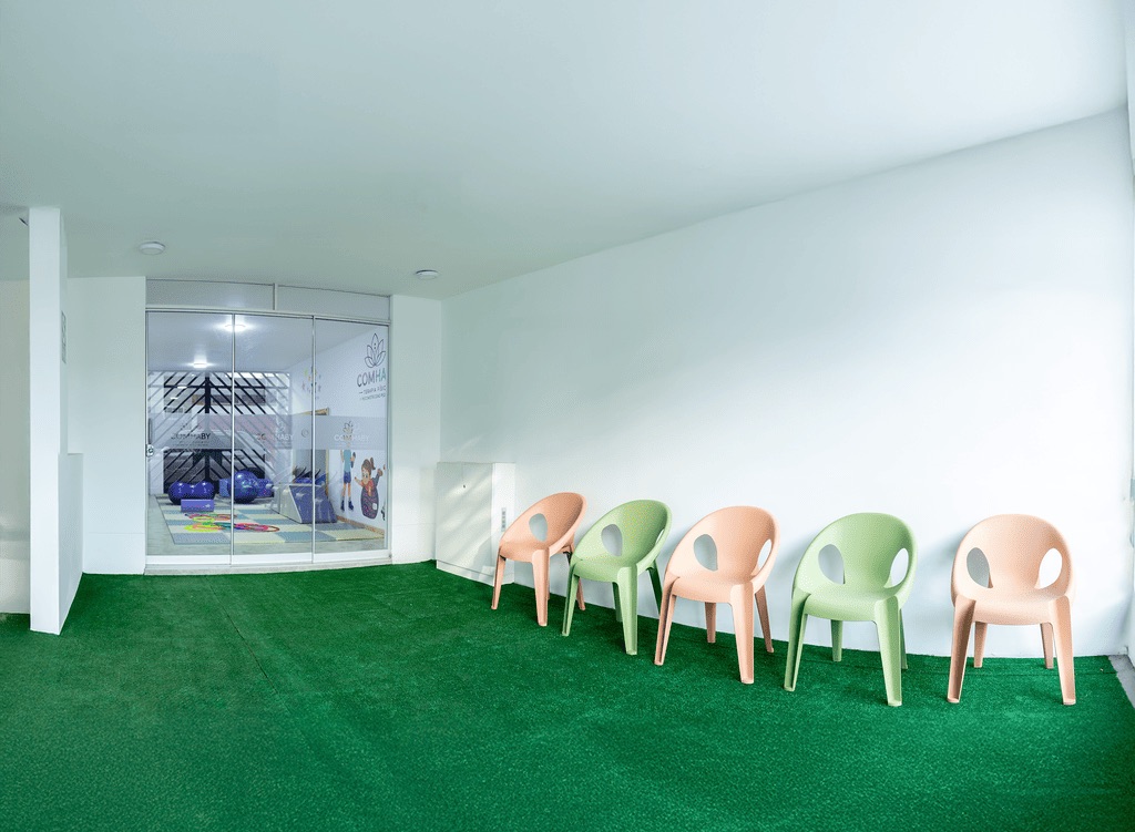Sala de espera infantil de COMHABY con sillas de colores y césped sintético